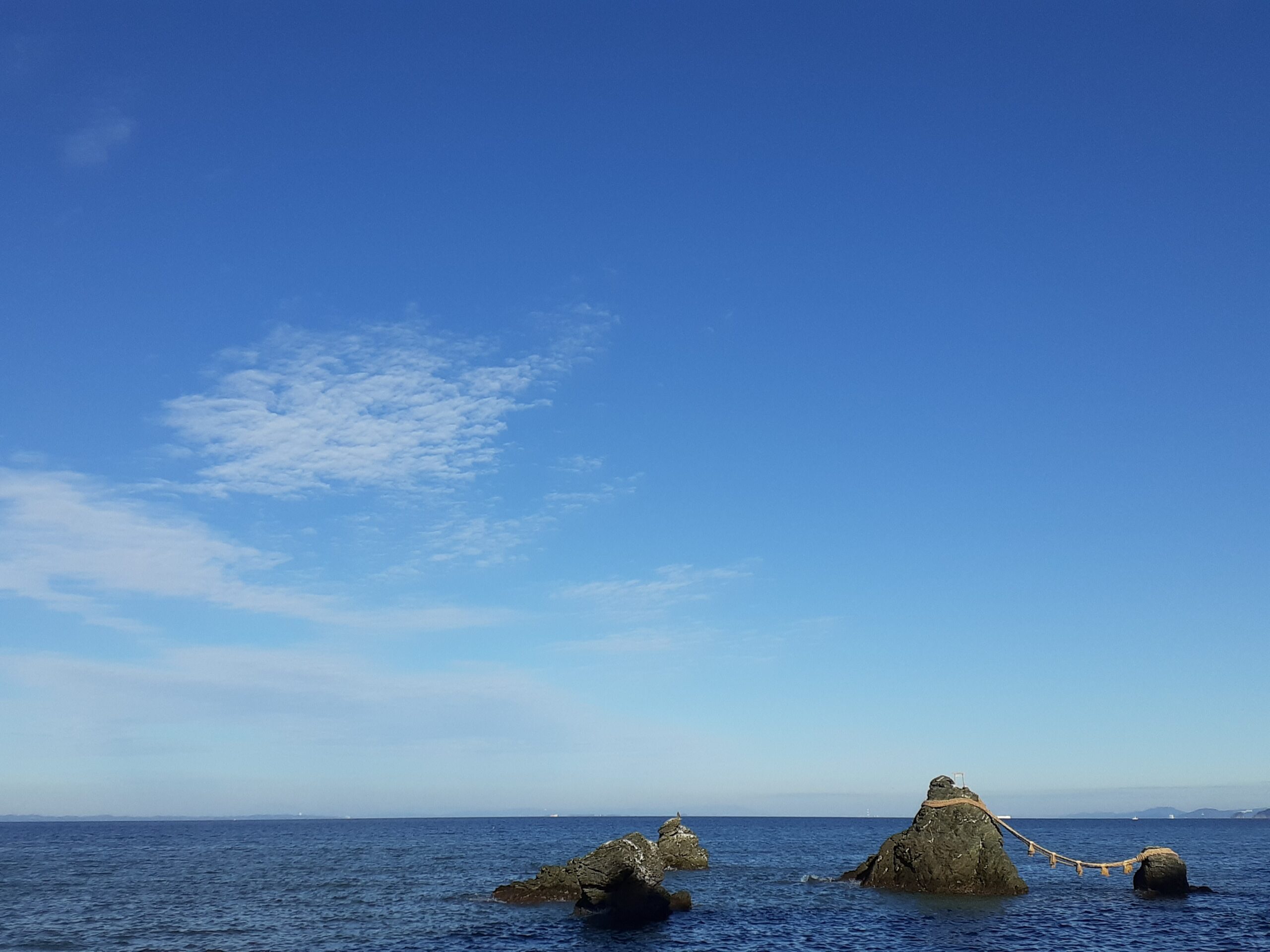 伊勢の夫婦岩の写真。青空と海、水平線と遠くに写る小さな船と、青いコントラストの一枚。エネルギーに満ち満ち溢れた自分の心に話しかけたくなる、感覚的、視覚的、直感、精神性を大切に生きるが見えてくる写真。